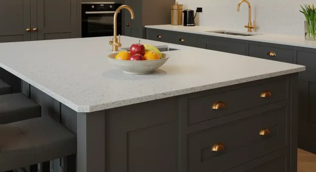 Kitchen island with charcoal gray cabinets, quartz countertop, and brass accents.